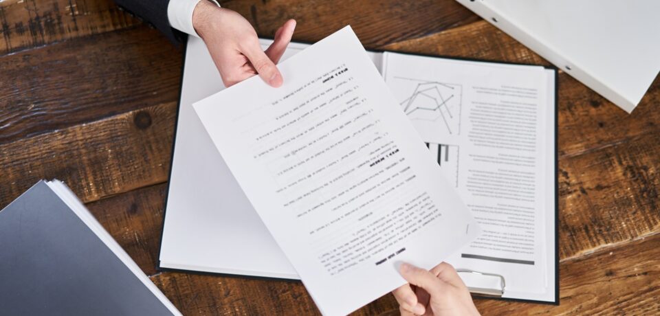 document-exchange-between-colleagues-on-wooden-des-2026-01-08-23-41-33-utc (Duże) Umowa na obsługę informatyczną firmy — co musi zawierać w 2026 roku