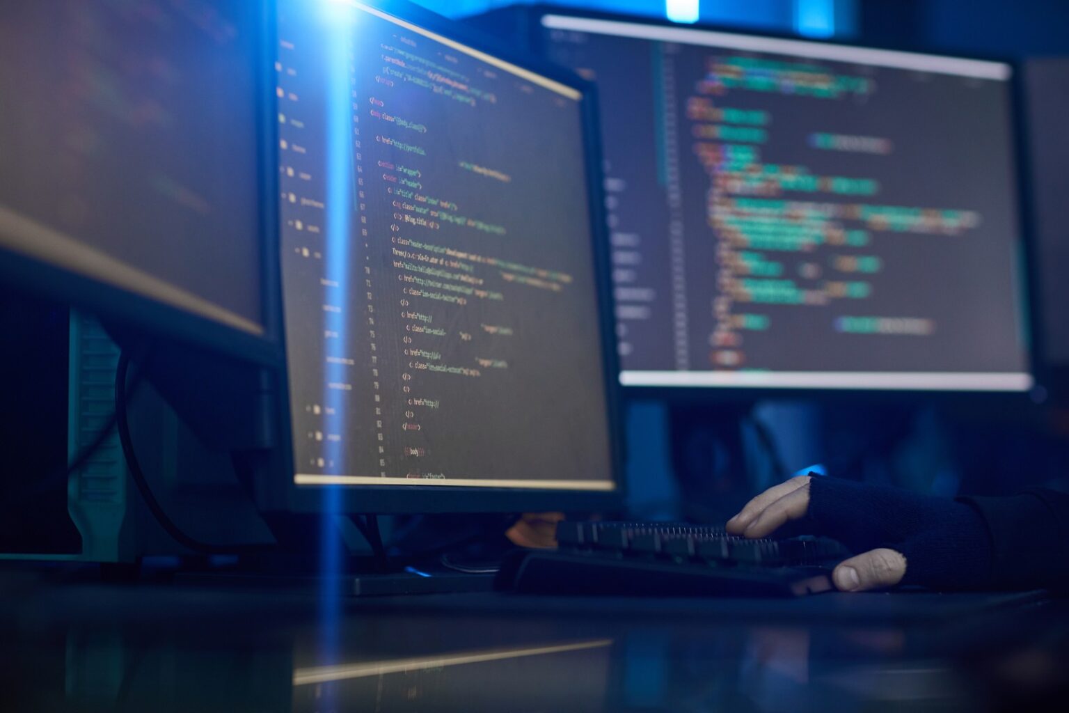 Outsourcing programistów 2 Monitory z kodem źródłowym w pokoju zespołu programistów