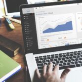 Mężczyzna pracujący na laptopie z wykresami biznesowymi na ekranie