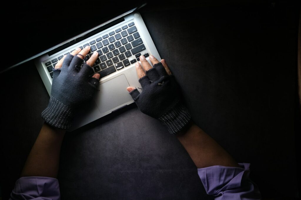 Testy penetracyjne 3 Osoba w rękawiczkach pisze na laptopie – symulacja ataku