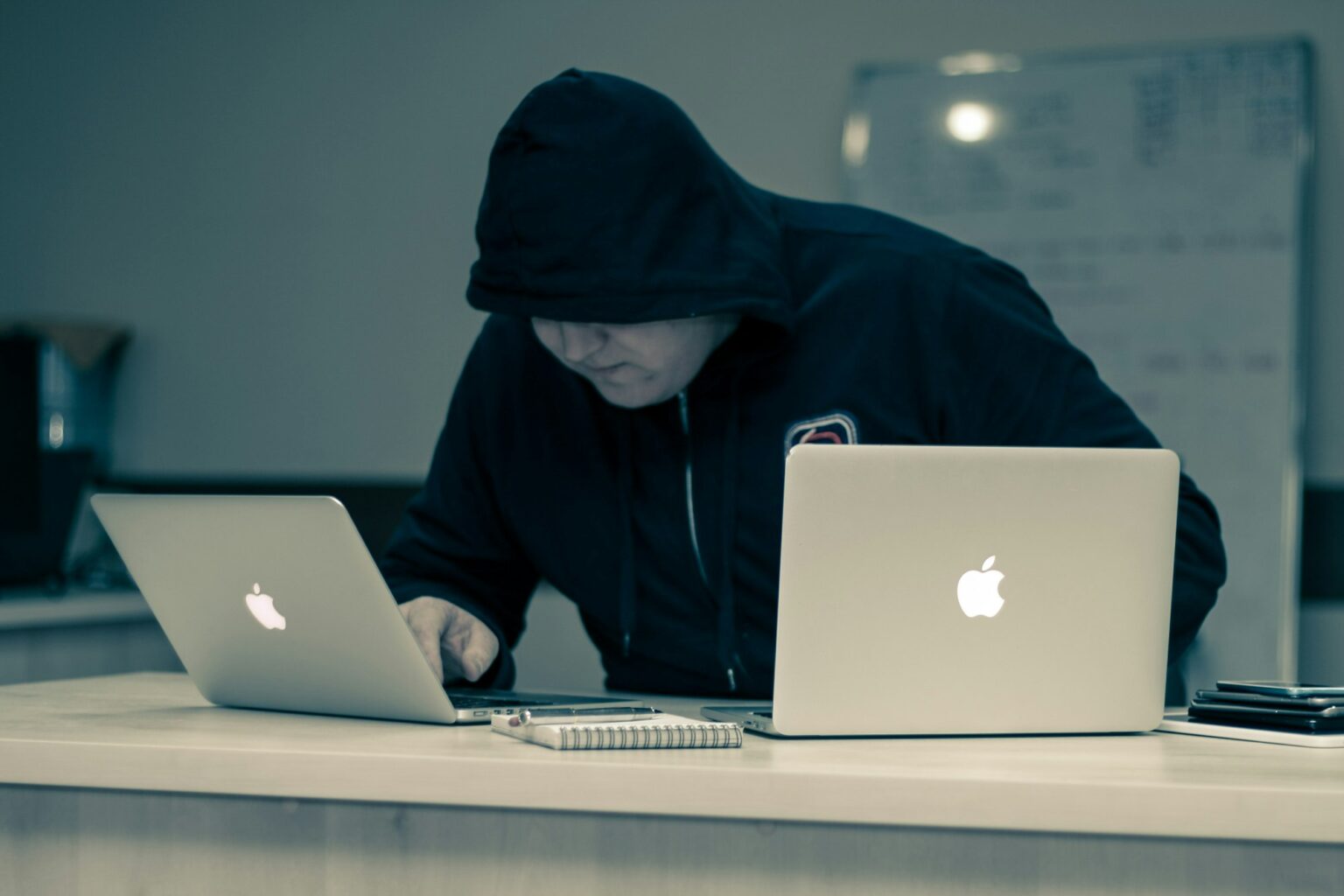 Osoba w kapturze przy laptopie – socjotechnika