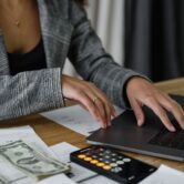 Copilot Credits – koszty agentów AI w Microsoft 365 Pracownica przy laptopie i kalkulatorze sprawdza koszty – rozliczanie agentów Copilot w Copilot Credits