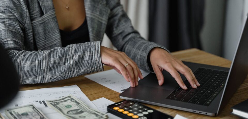Copilot Credits – koszty agentów AI w Microsoft 365 Pracownica przy laptopie i kalkulatorze sprawdza koszty – rozliczanie agentów Copilot w Copilot Credits