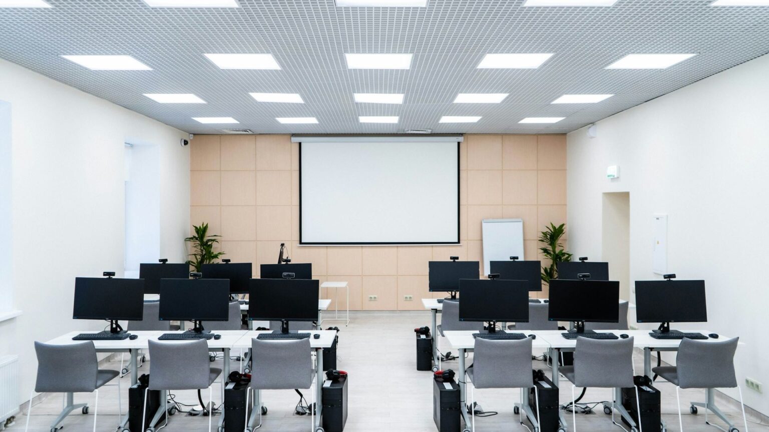 Sala komputerowa w szkole z monitorami na stołach — obsługa informatyczna szkół
