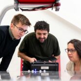 STEM Lokalnie – granty dla szkół ponadpodstawowych Uczeń, nauczycielka i inżynier testują urządzenie pomiarowe w szkolnej pracowni STEM